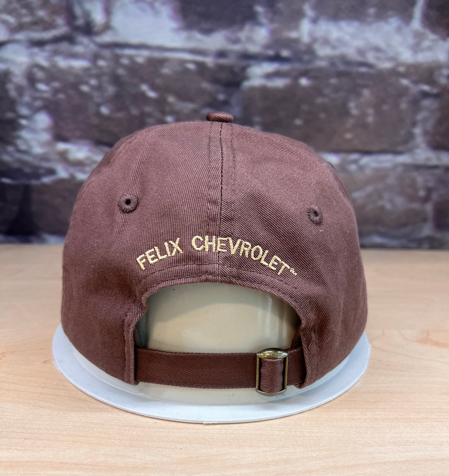Brown cap with 'Felix Chevrolet' logo on a wooden surface
