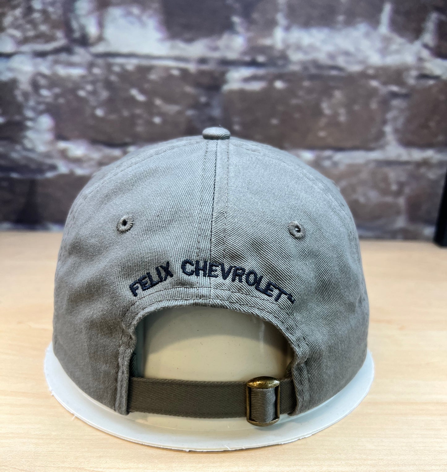 Gray cap with 'Felix Chevrolet' logo on a wooden surface