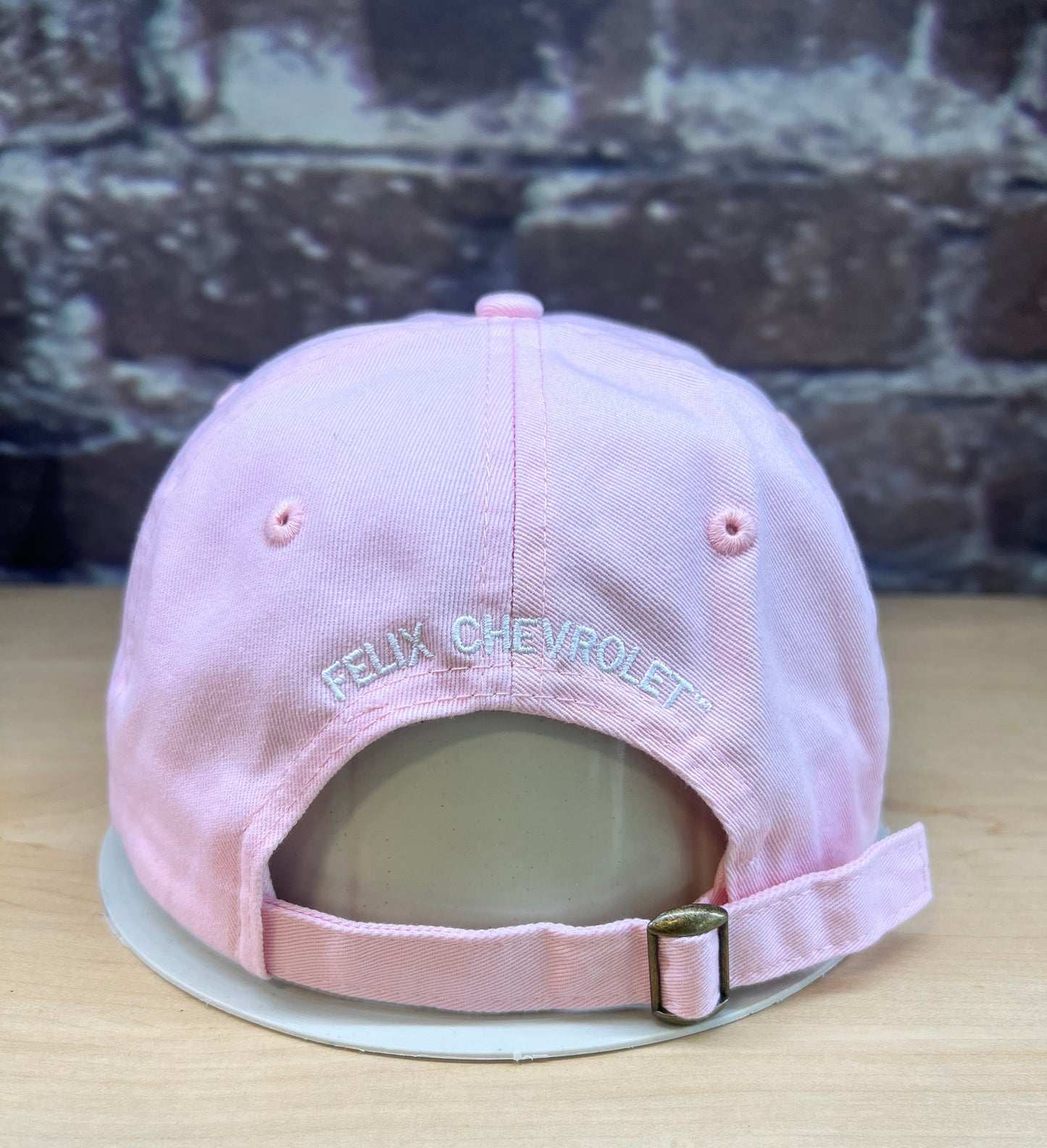 Pink  felix the cat cap with Chevrolet logo on a wooden surface